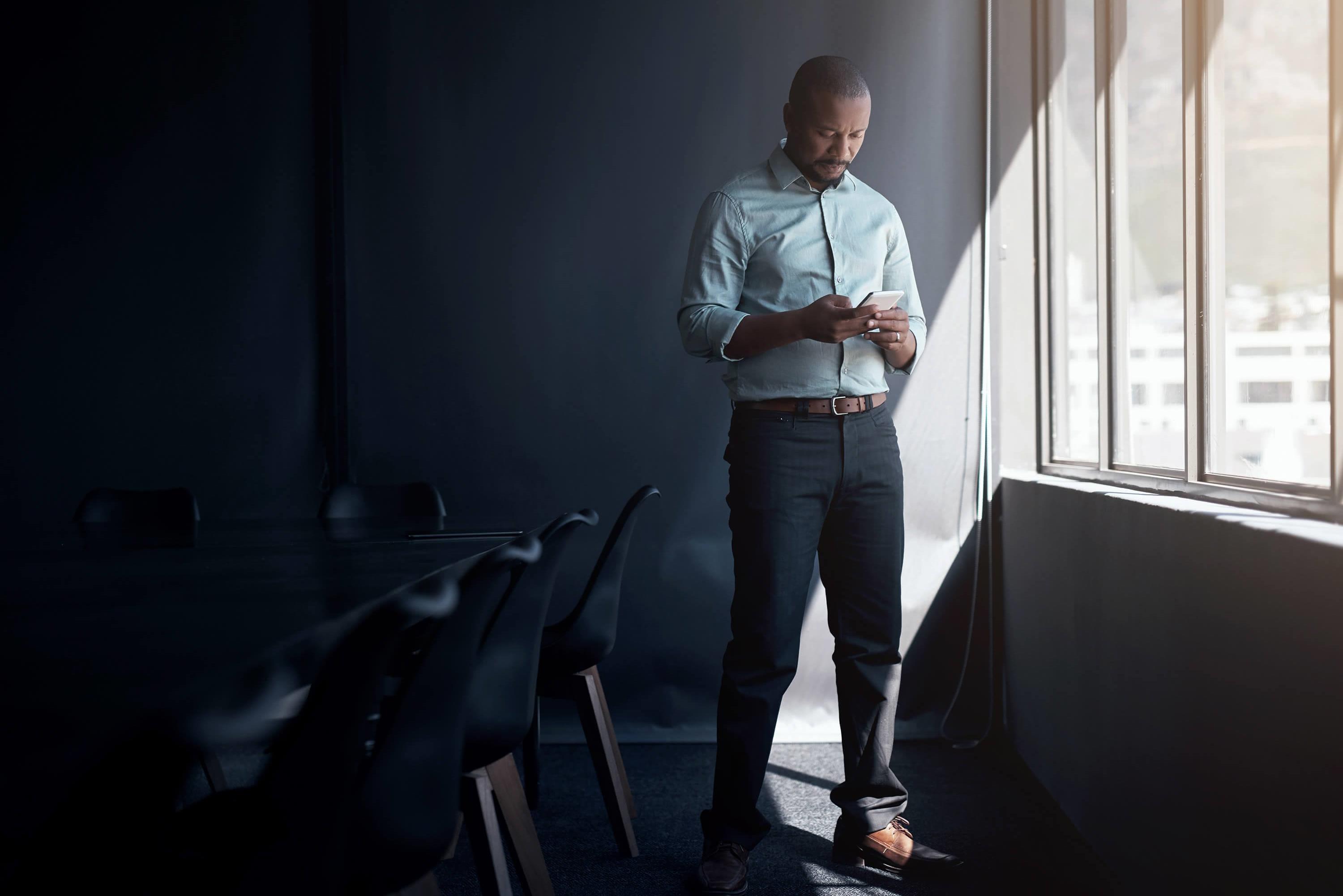 Man dress in business casual looking at his phone.